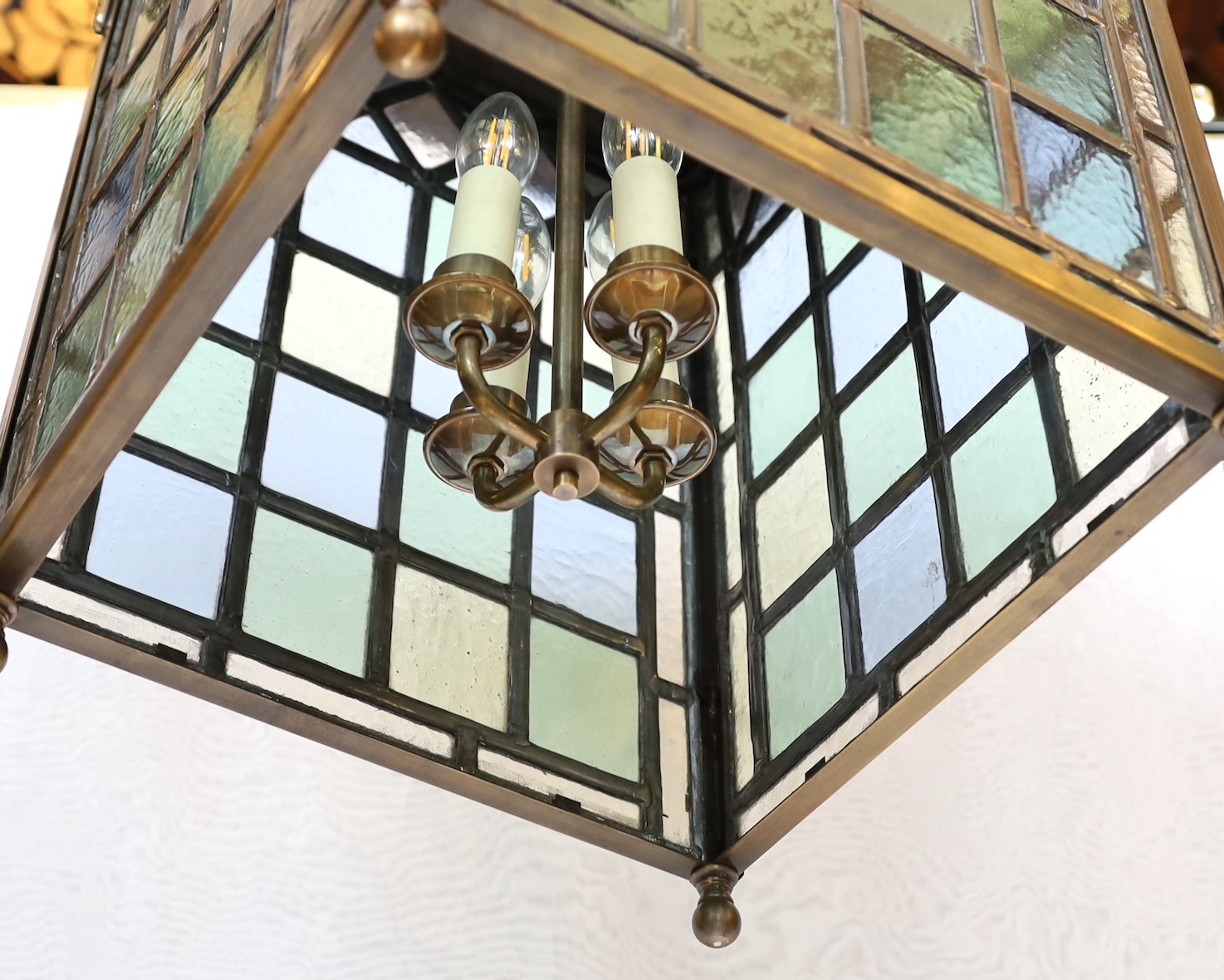 A large Edwardian lacquered brass and leaded glass hall lantern applied with rams head motifs, height 70cm. width 46cm